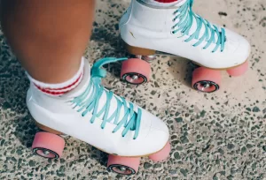 Cute pair of white roller blades with pink wheels and blue laces.