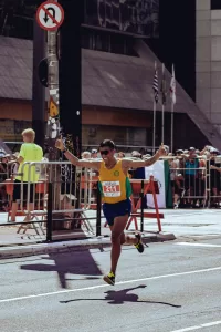 A man crossing the finish line at a running competition with a huge smile.