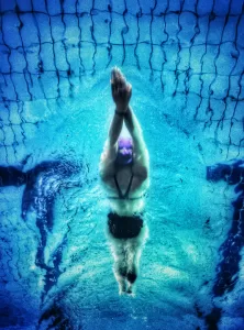 A person swimming under water in a big swimming pool.