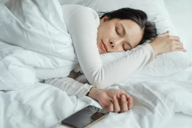 A woman sleeping in white sheets.